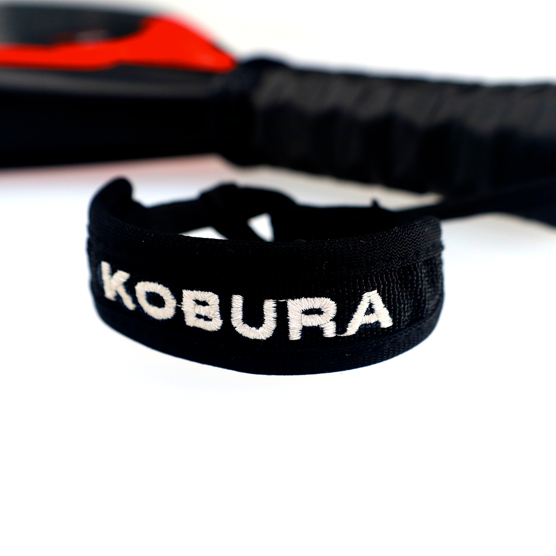 Close up of the wristband with logo on the Kobura Apex Pro 3K padel racket
